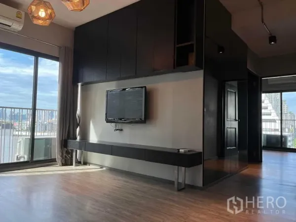 公寓 出售在Phaya Thai, Bangkok - 明亮客厅，内置电视墙与落地窗，阳台可观城市景色，帕亚泰