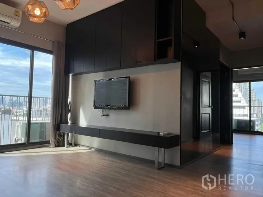 公寓 出售在Phaya Thai, Bangkok - 明亮客厅，内置电视墙与落地窗，阳台可观城市景色，帕亚泰