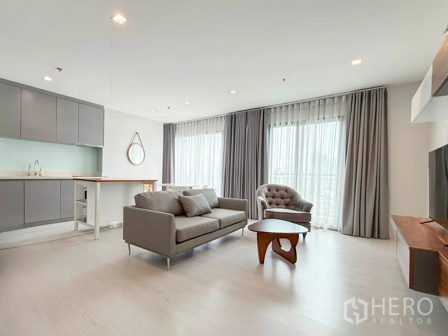 Condominium for rent in Khlong Toei, Bangkok - Wide view of living, kitchen, and dining with natural light and sheer curtains.