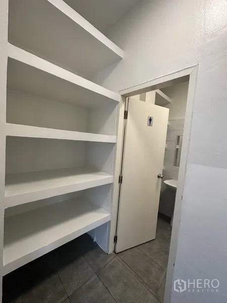 พื้นที่ขายปลีก ให้เช่าในBang Rak, Bangkok - ชั้นวางของบิลท์อินสีขาวติดกับประตูไปยังห้องน้ำส่วนตัว.