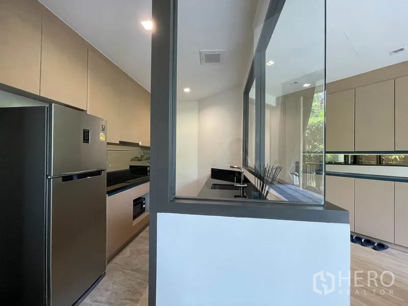 คอนโด ขายในWatthana, Bangkok - ครัวปิดสไตล์แกลลีย์ ผนังกั้นกระจก ท็อปสีดำ และตู้เย็นสแตนเลส