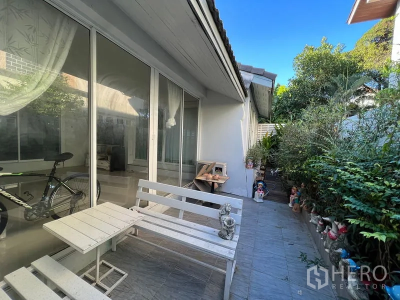 บ้าน ขายในLat Krabang, Bangkok - ลานหลังบ้านพร้อมม้านั่งไม้สีขาว ผนังกระจกบานใหญ่ และสวนเขียว