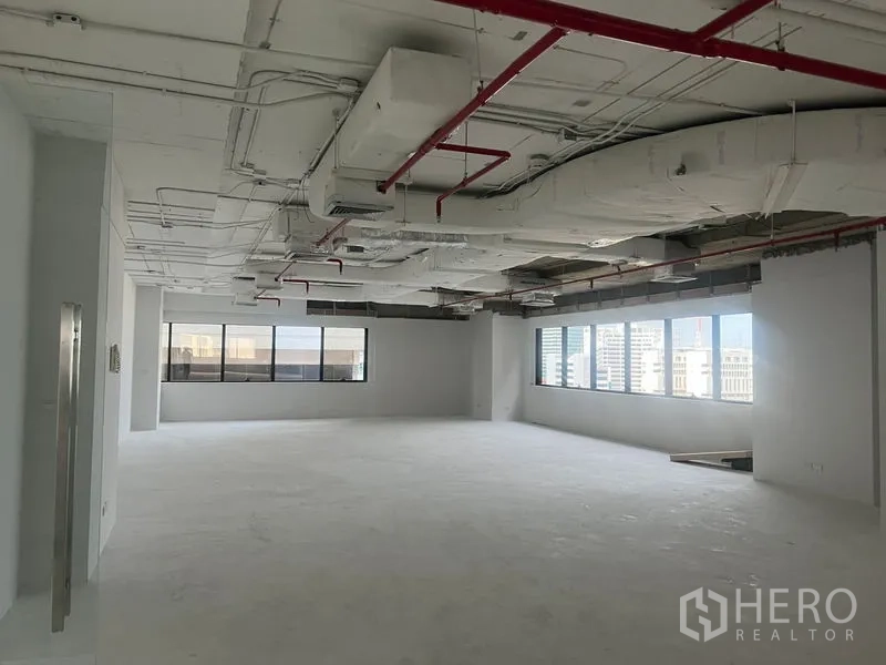สำนักงาน ให้เช่า - พื้นที่สำนักงานแบบเปิดกว้าง เพดานเปลือยพร้อมท่อดักท์และระบบสปริงเกลอร์ สีแดง มีหน้าต่างบานใหญ่พร้อมวิวเมือง