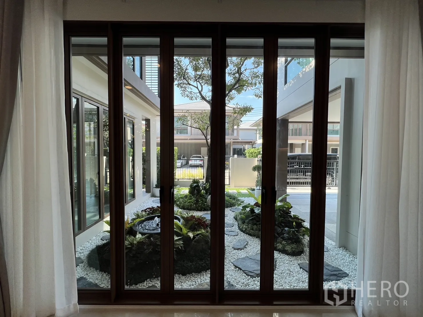 Detached House for rent or sale in Bang Kapi, Bangkok - Garden view from inside through tall sliding doors to the rock and pebble courtyard.