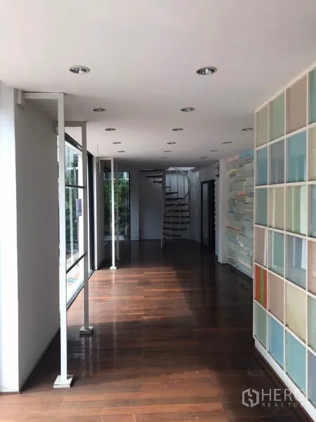 零售空间 出租在Watthana, Bangkok - 明亮展厅，木地板、格架墙与靠近玻璃的旋转楼梯