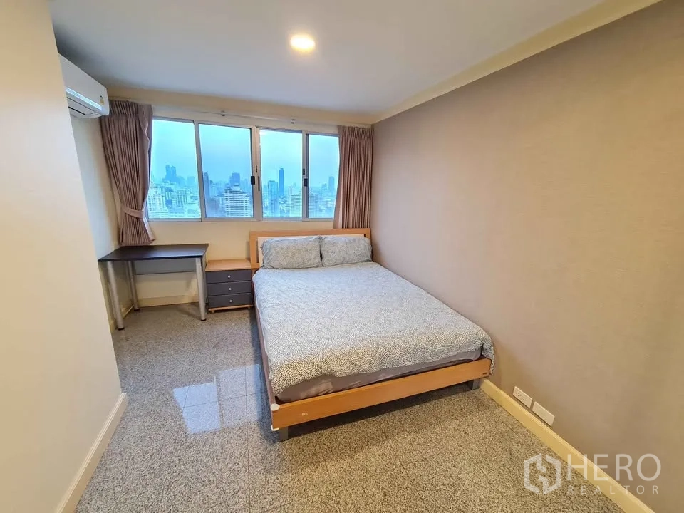 Condominium for rent in Khlong Toei, Bangkok - Second bedroom with bed, desk and panoramic windows.