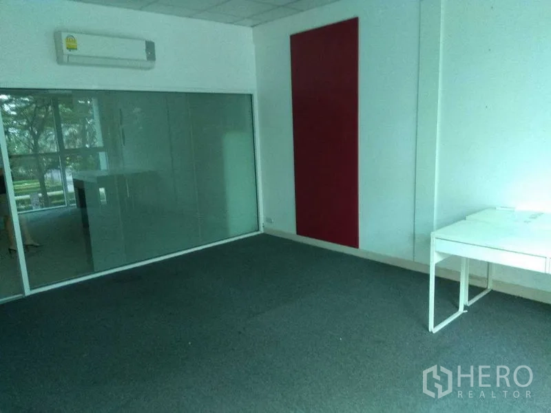 零售空间 出租在Huai Khwang, Bangkok - 铺地毯的展厅或办公室，磨砂玻璃墙和红色装饰板。