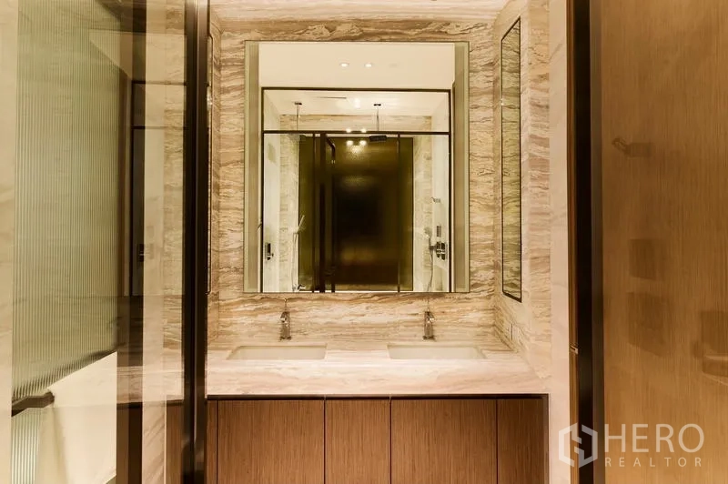 Condominium for rent in Pathum Wan, Bangkok - Luxurious bathroom with double vanity, marble countertop and a large mirror.