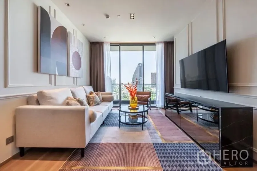 Condominium for rent in Khlong Toei, Bangkok - Spacious lounge with sofa, wall art, large TV and balcony-style windows to the skyline.