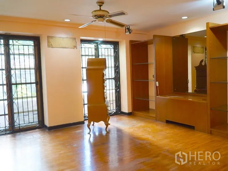 Townhouse for rent in Pathum Wan, Bangkok - Large room with wooden floors, display shelves and a ceiling fan.