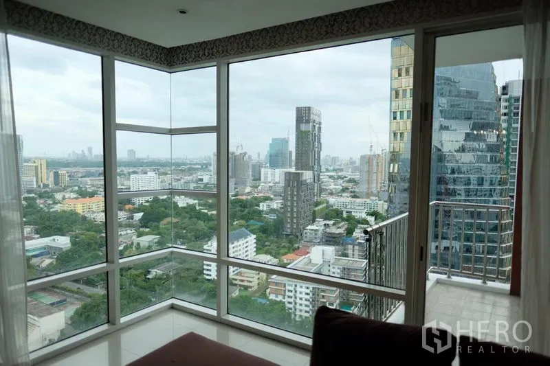 Condominium for rent in Watthana, Bangkok - Corner room with wraparound floor-to-ceiling windows, city views and access to a small balcony.