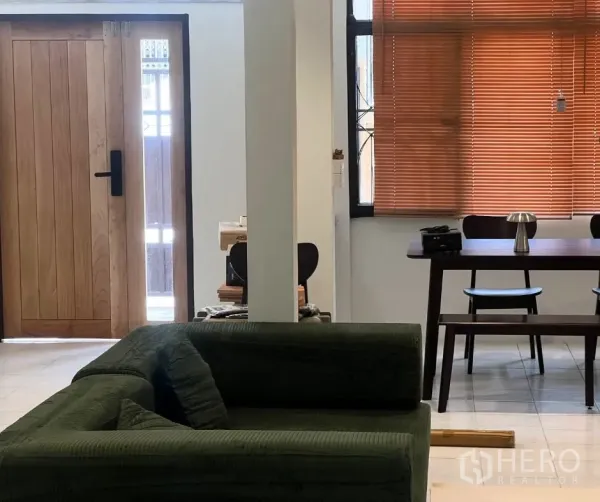ทาวน์เฮาส์ ให้เช่า - พื้นที่นั่งเล่นและทานอาหารแบบโอเพ่น มีโซฟาสีเขียว ประตูไม้ และมู่ลี่