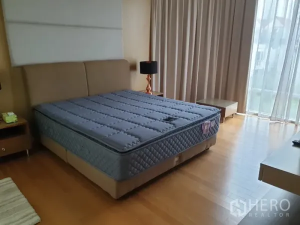 Condominium for rent in Watthana, Bangkok - Spacious master bedroom with king bed, floor-to-ceiling windows, blackout curtains and hardwood floors.