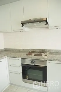 Condominium for rent in Pathum Wan, Bangkok - Modern kitchen with granite counters, electric hob, oven and range hood.