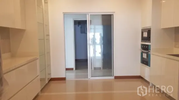 Condominium for rent or sale in Yan Nawa, Bangkok - Kitchen with long countertops and a glass sliding door to the utility area.