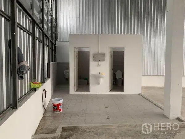 货栈 出租在Mueang Pathum Thani, Pathum Thani - 仓内卫生间区域，设有坐便与洗手盆，金属夹层墙体。