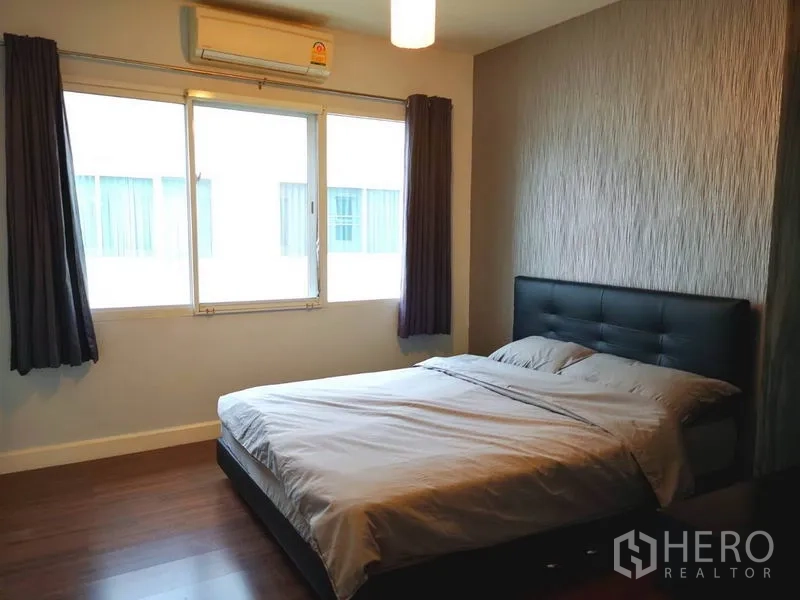 Townhouse for rent in Suan Luang, Bangkok - Bright bedroom with double bed, air conditioning and textured feature wall.
