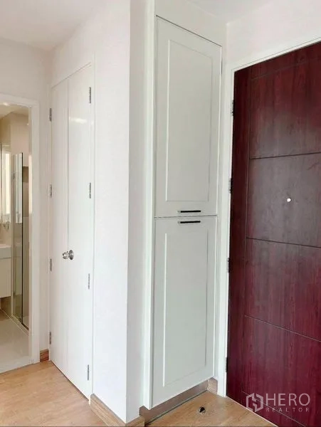Condominium for rent in Watthana, Bangkok - Entry hallway of Watthana condo with solid wood door, white built‑in cabinet and bathroom access.