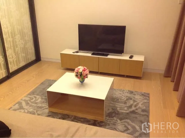 Condominium for rent or sale in Watthana, Bangkok - Living room with TV console, coffee table and patterned area rug