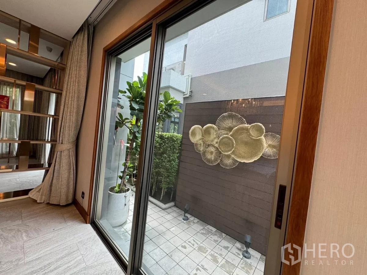 Detached House for rent in Prawet, Bangkok - Sliding door to a tiled patio with privacy wall art and potted plants.