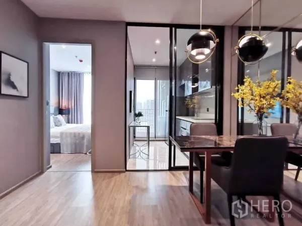 คอนโด ขายในWatthana, Bangkok - พื้นที่รับประทานอาหารพร้อมโคมไฟ ดีไซน์โมเดิร์น ประตูกระจกกั้นครัวและทางออกสู่ระเบียง พื้นไม้ และมองเห็นห้องนอน คอนโดใกล้ BTS เอกมัย
