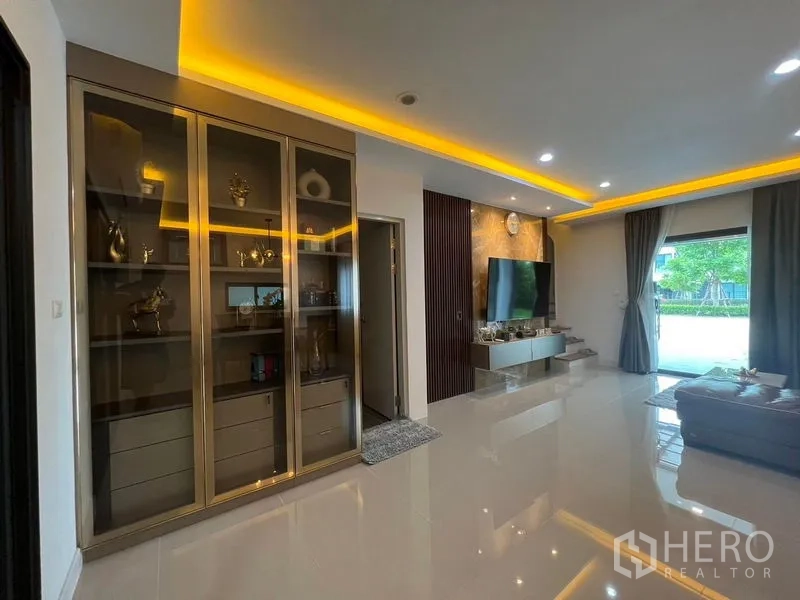 ทาวน์เฮาส์ ให้เช่า - มุมห้องนั่งเล่นพร้อมตู้โชว์บิลท์อิน ผนังทีวลายหินอ่อน และไฟดาวน์ไลท์