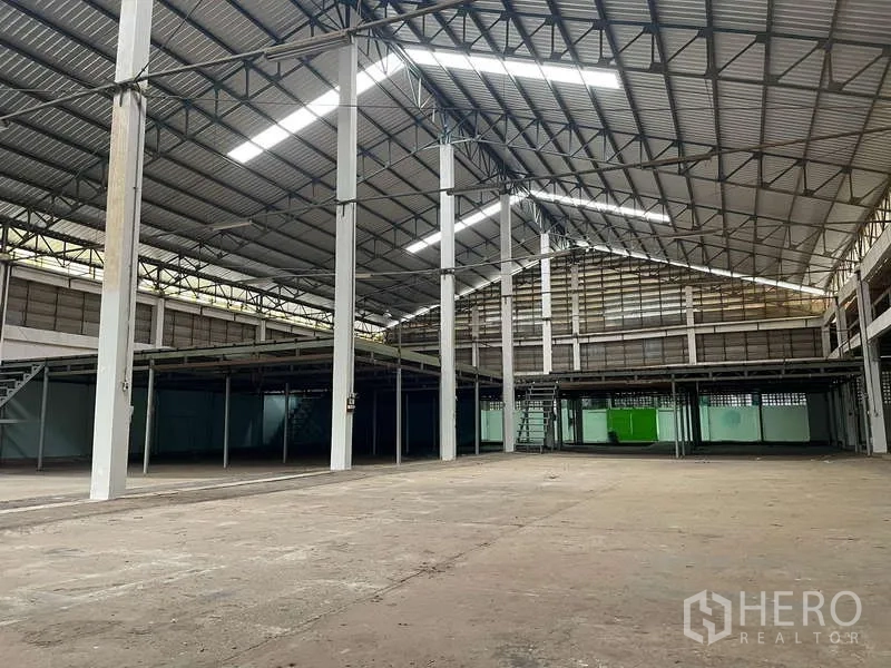 Warehouse for rent in Nong Khaem, Bangkok - Open warehouse floor with tall columns, steel rafters and raised mezzanine storage.
