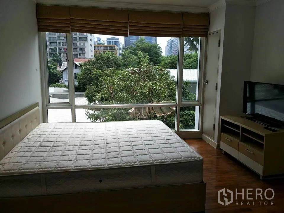 公寓 出租在Khlong Toei, Bangkok - 卧室配大床，落地窗带城市与树梢景观，百叶窗与电视柜一应俱全