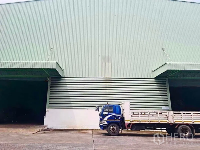 Warehouse for rent in Phra Pradaeng, Samut Prakan - Warehouse loading bays with a parked flatbed truck on a paved yard