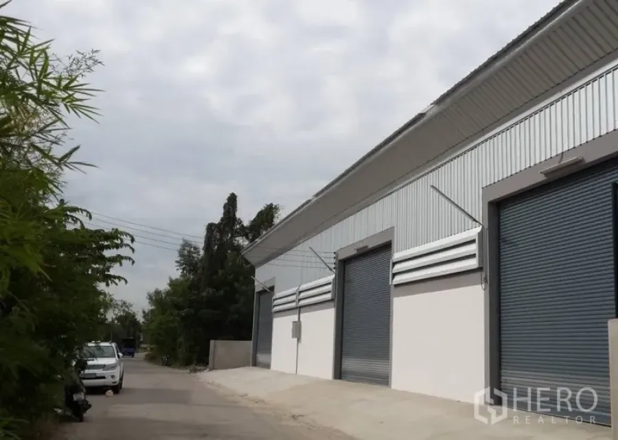 คลังสินค้า ให้เช่าในNonthaburi - ด้านหน้าโกดังสมัยใหม่ ผนังเมทัลชีทพร้อมประตูม้วนหลายบาน อยู่ในซอยเงียบ