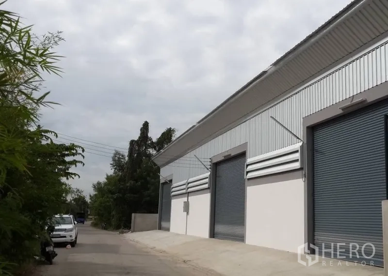 คลังสินค้า ให้เช่าในNonthaburi - ด้านหน้าโกดังสมัยใหม่ ผนังเมทัลชีทพร้อมประตูม้วนหลายบาน อยู่ในซอยเงียบ