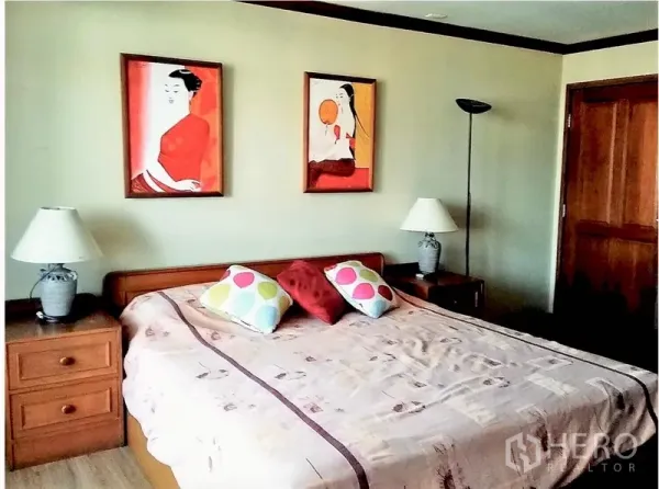 Condominium for rent or sale in Watthana, Bangkok - Cozy secondary bedroom with bedside tables, lamps, colorful cushions, and framed wall art.