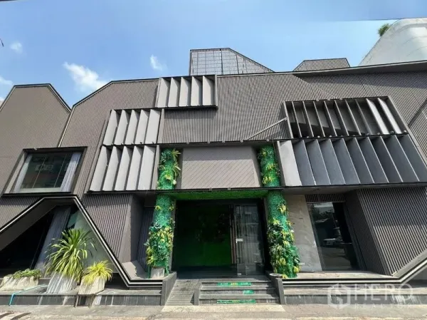 零售空间 出租在Din Daeng, Bangkok - 现代零售建筑外立面，深色金属格栅与入口竖向绿植，位于曼谷。