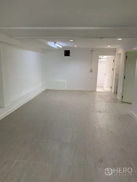 店屋 出租在Bang Na, Bangkok - 修长房间，浅色地砖与白墙，尽头通向服务区的门。