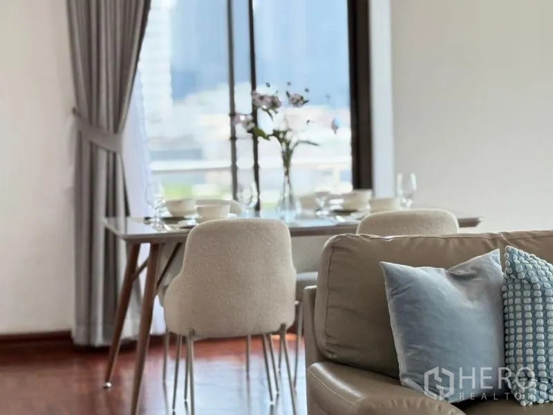 Condominium for rent - Detail of dining table and upholstered chairs beside a sofa with accent cushions.