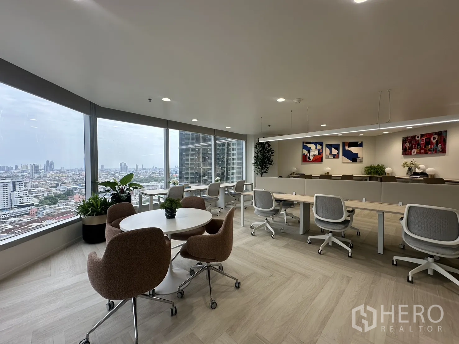 Office Space for rent in Sathon, Bangkok - Spacious office floor with rows of workstations, a round meeting table, and wide windows with a city view.
