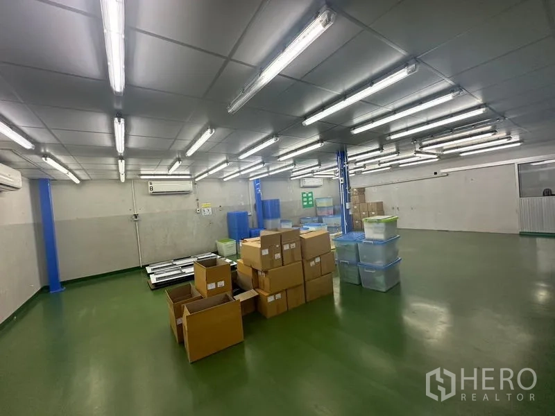 คลังสินค้า ให้เช่าหรือขายในLam Luk Ka, Pathum Thani - พื้นที่เก็บของขนาดใหญ่ ไฟฟลูออเรสเซนต์ กล่องและลังพลาสติกบนพื้นสีเขียว