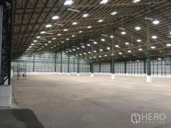 货栈 出租在Mueang Pathum Thani, Pathum Thani - 宽敞仓库内景，高钢结构屋顶，明亮LED照明与混凝土地坪
