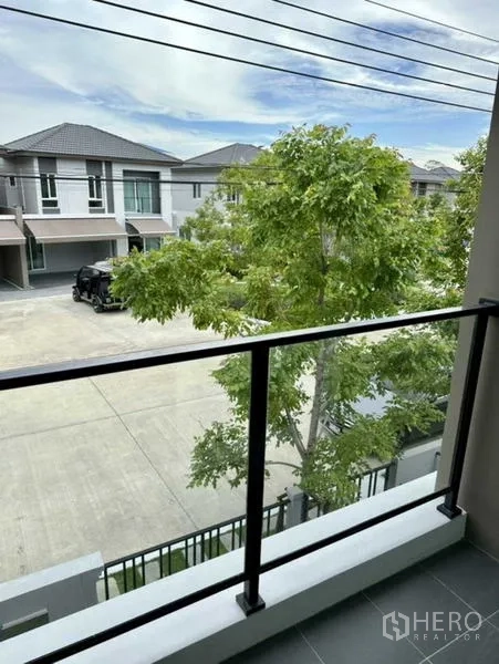 Townhouse for rent in Bang Phli, Samut Prakan - Balcony view over peaceful street with trees and neighboring townhouses.