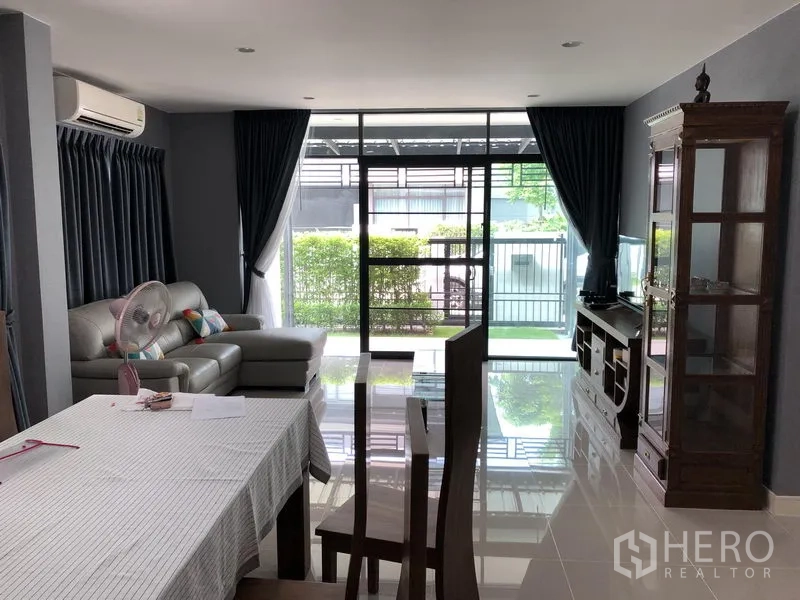 Detached House for rent in Bang Kapi, Bangkok - Bright living room with large glass doors to a small garden, sofa set and media cabinet.