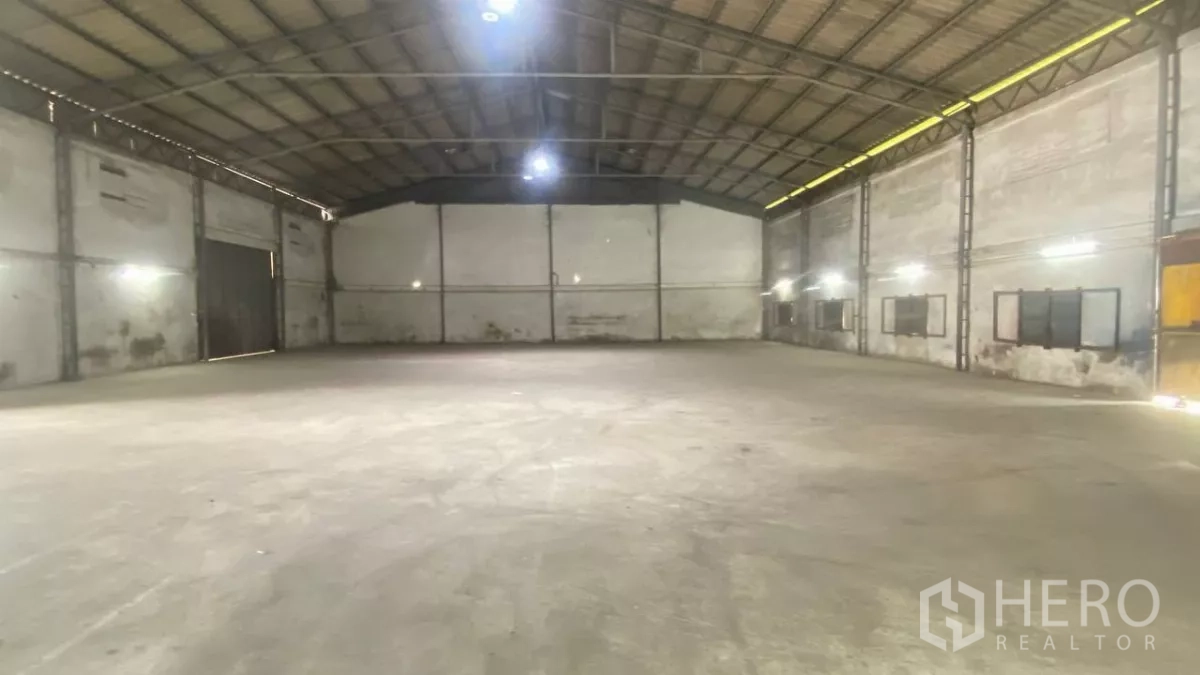 Factory for rent in Bang Sao Thong, Samut Prakan - Clear-span warehouse interior with high steel truss roof and smooth concrete floor.