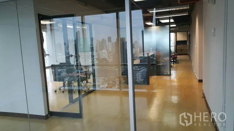 办公空间 出租在Khlong Toei, Bangkok - 带玻璃隔断的办公室与会议室，窗外可见曼谷天际线（Phra Khanong）。