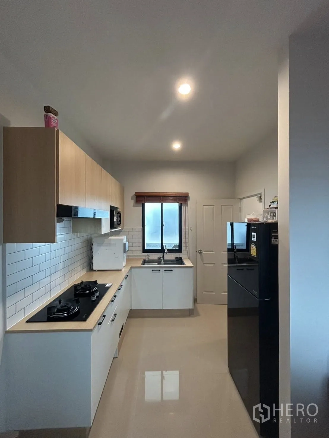 Detached House for rent in Khlong Sam Wa, Bangkok - Modern closed kitchen with white cabinetry, gas hobs and appliances.