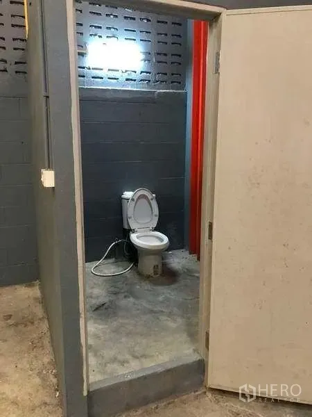 工厂 出租在Phra Pradaeng, Samut Prakan - 厂房内简单卫生间，混凝土墙面与地面可见坐便器。