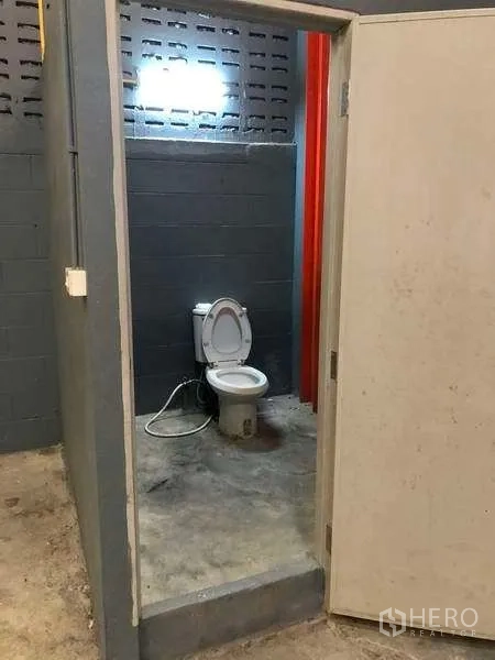 工厂 出租在Phra Pradaeng, Samut Prakan - 厂房内简单卫生间，混凝土墙面与地面可见坐便器。