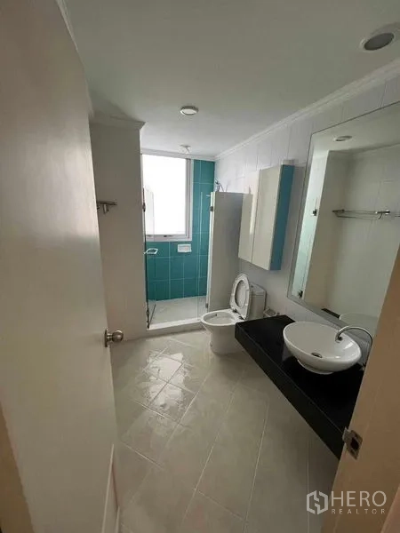 Condominium for sale in Sathon, Bangkok - Bathroom with vessel sink, mirrored cabinet, toilet, and a windowed shower area.