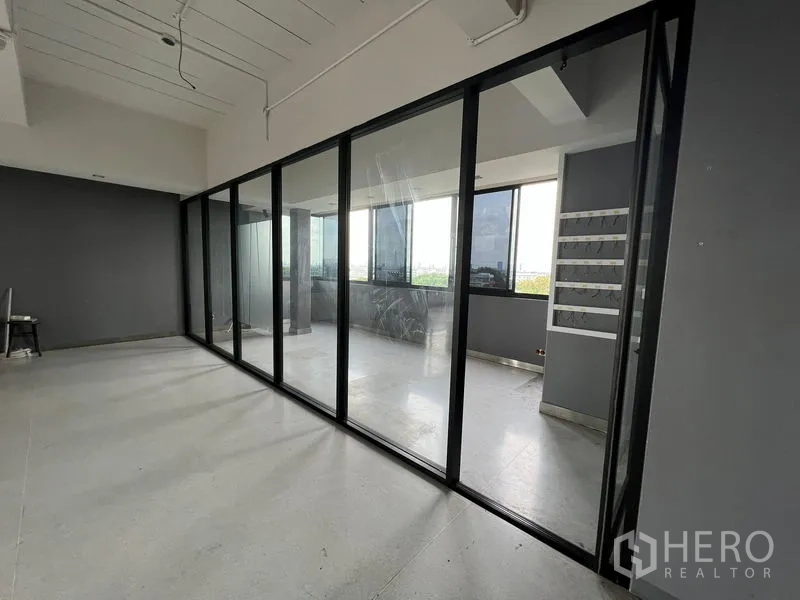 Office Space for rent in Mueang Samut Prakan, Samut Prakan - Workspace lined with floor-to-ceiling glass partition opening to a balcony area.