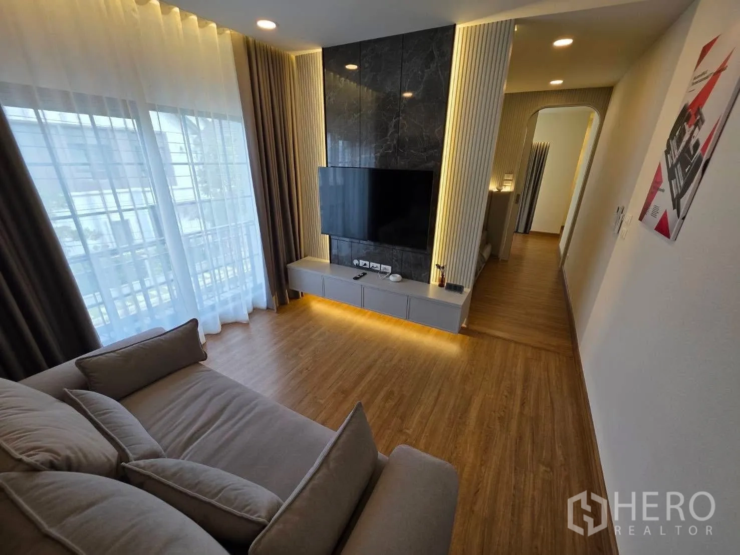 Detached House for rent or sale in Bang Phli, Samut Prakan - Upstairs family lounge with sofa, TV feature wall and sheer curtains.