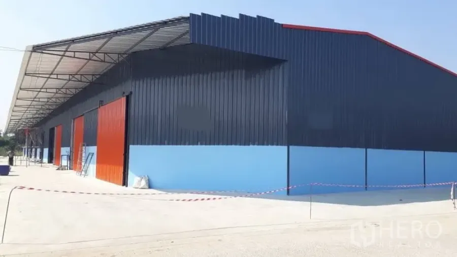 คลังสินค้า ให้เช่าในPak Kret, Nonthaburi - โกดังโครงสร้างเหล็กสีน้ำเงินในปากเกร็ด ประตูบานเลื่อนสีส้ม พร้อมลานคอนกรีตกว้างและกันสาดขนถ่ายยาว