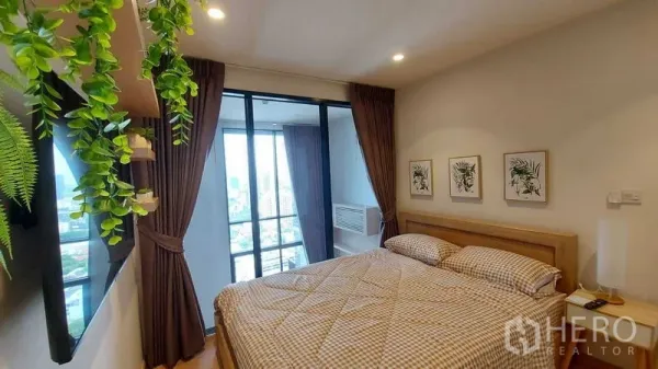 Condominium for rent in Watthana, Bangkok - Bright bedroom with large bed, balcony and floor-to-ceiling windows offering city views.